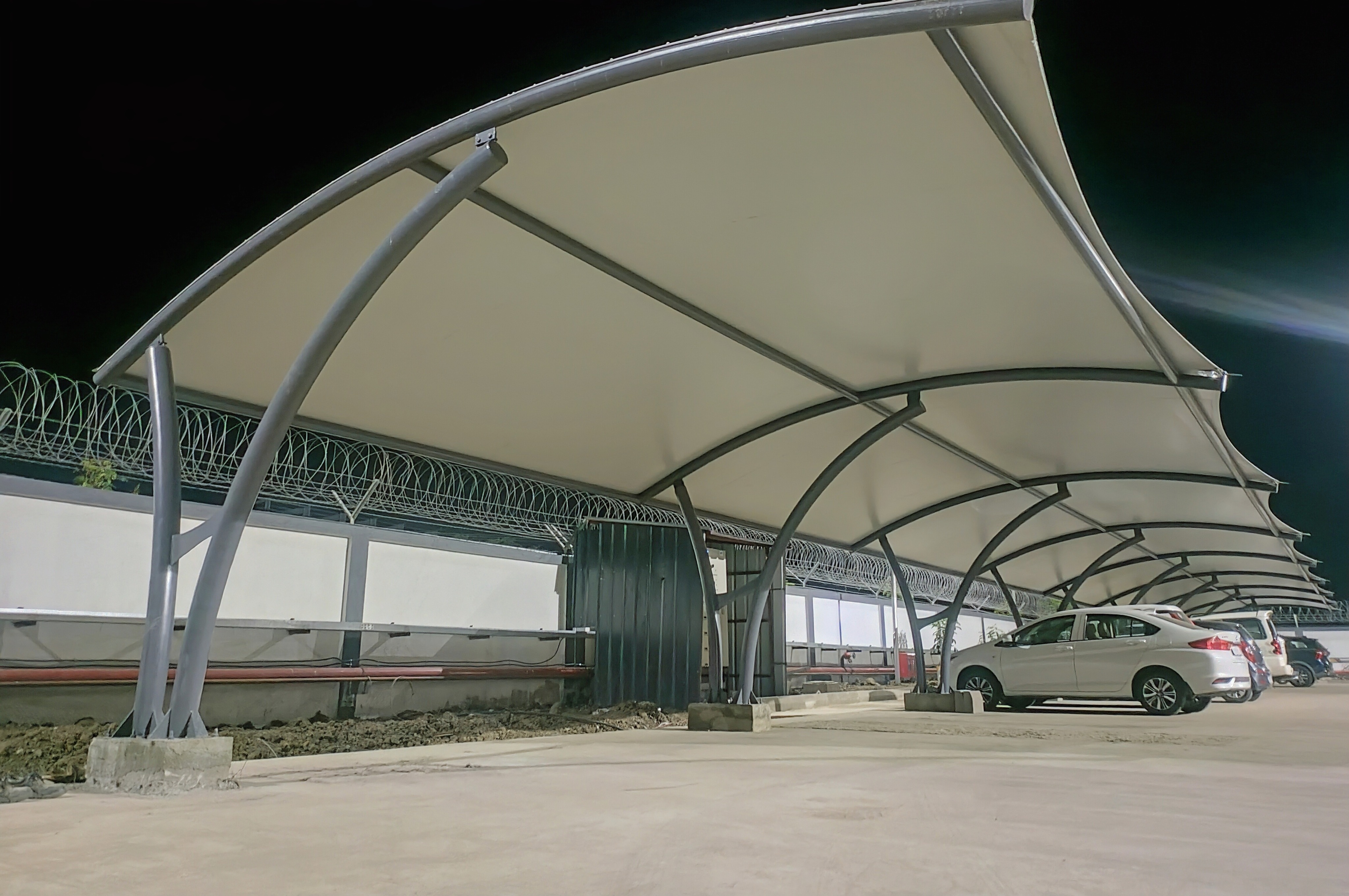 Row of sweeping cantilever parking canopies at night